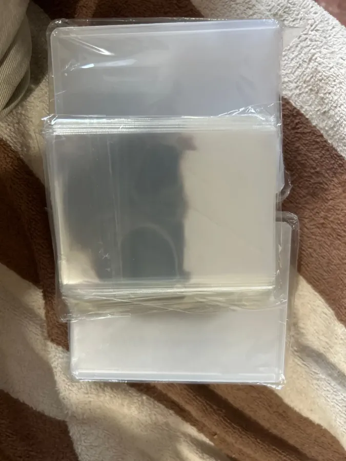 Buyer photo of sealed sleeve and toploader packs on a blanket