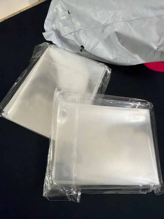 Buyer photo of two wrapped packs of clear card sleeves
